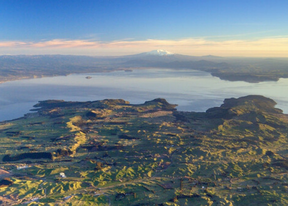 Aerial view of Lake Taupo from the north with volcanoes of the Tongariro National Park in the distance. Taupo township at left.