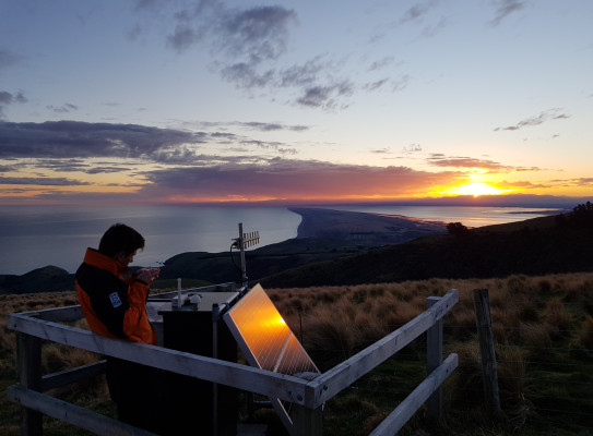 Feild tech Merijn aligning an antenna with a compass at our Te oka bay road site on Banks Peninsula looking over Kaitorete spit.