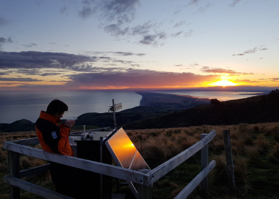 Feild tech Merijn aligning an antenna with a compass at our Te oka bay road site on Banks Peninsula looking over Kaitorete spit.